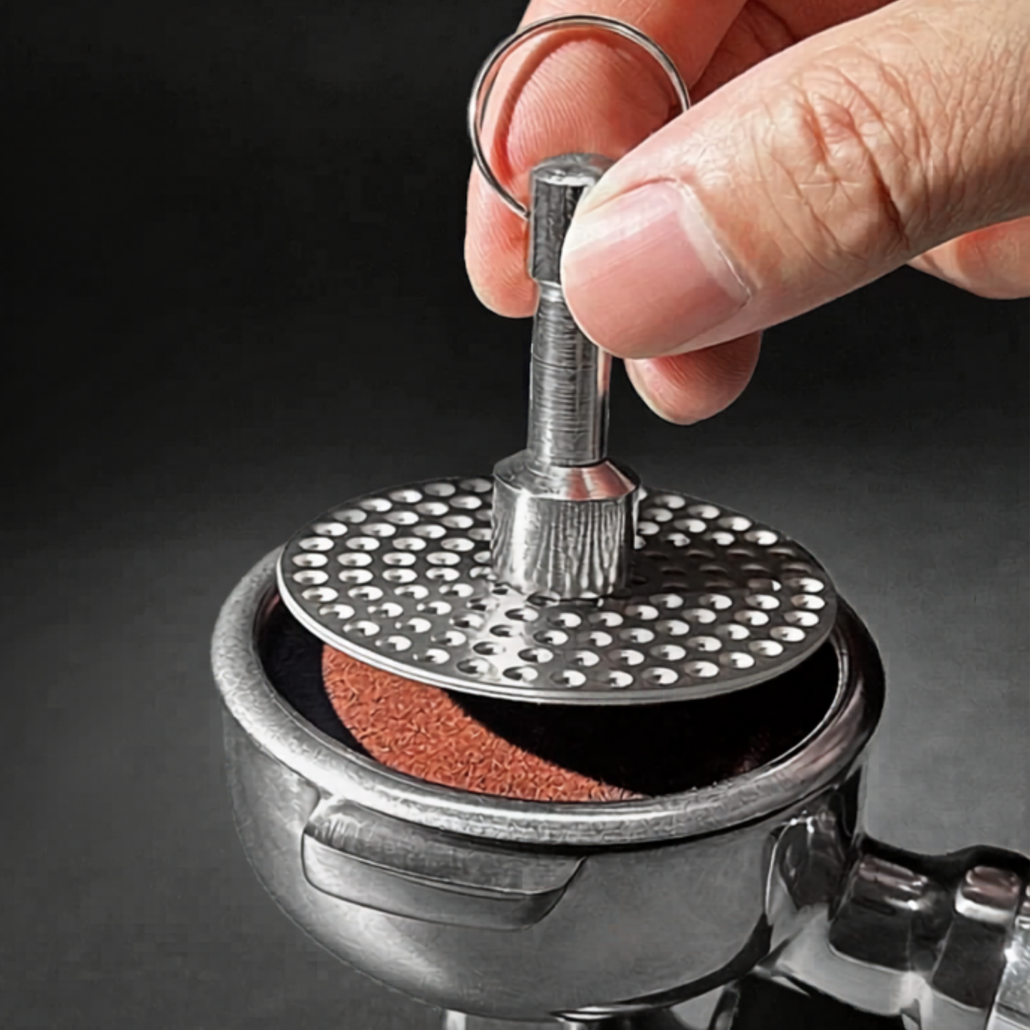 Magnetic remover lifting a reusable espresso puck screen from a portafilter.